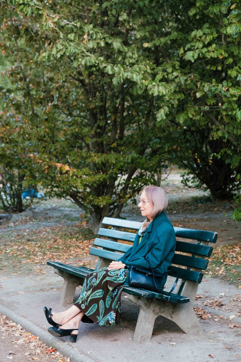 A woman sitting in a parc with autumn leaves